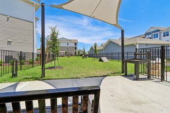 Fenced playground area with shade sails and green lawn